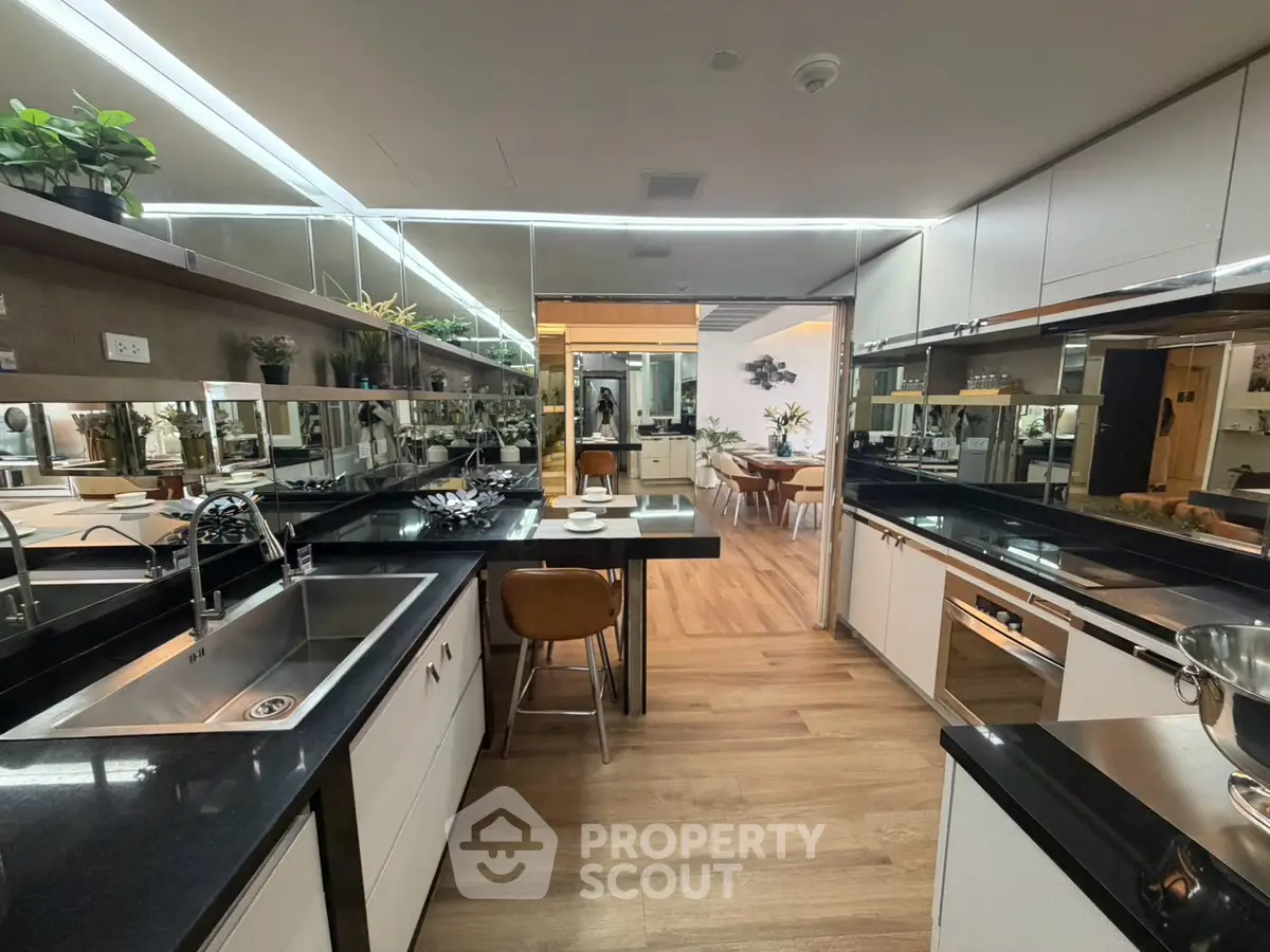 Modern kitchen with sleek black countertops and open layout leading to dining area.