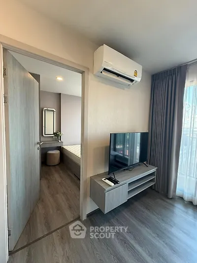 Modern living room with TV and air conditioning, leading to a cozy bedroom with natural light.