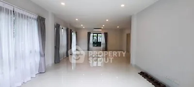 Spacious and bright living room with large windows and elegant curtains