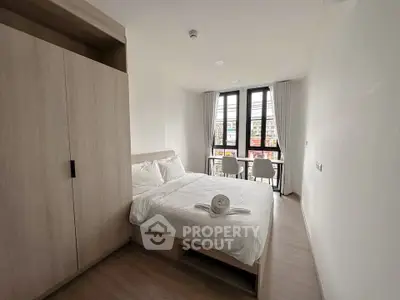 Modern bedroom with large windows and minimalist decor in a stylish apartment.
