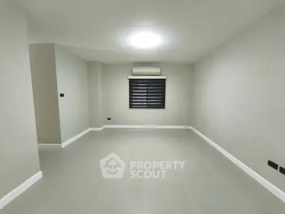 Spacious empty room with modern tile flooring and air conditioning, ready for customization.