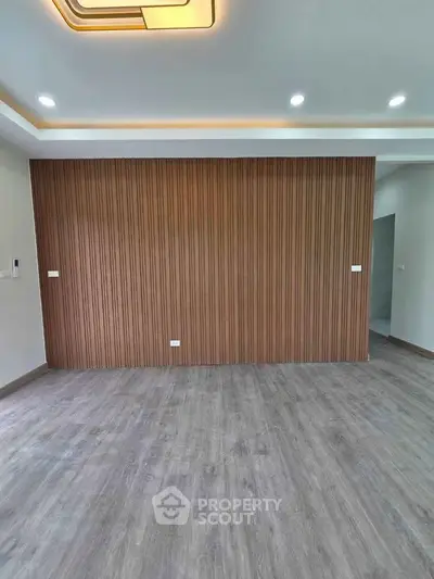 Spacious modern living room with elegant wood panel accent wall and sleek lighting.