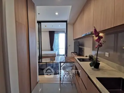 Modern studio apartment with open kitchen and cozy living area, featuring sleek wooden cabinetry and stylish decor.