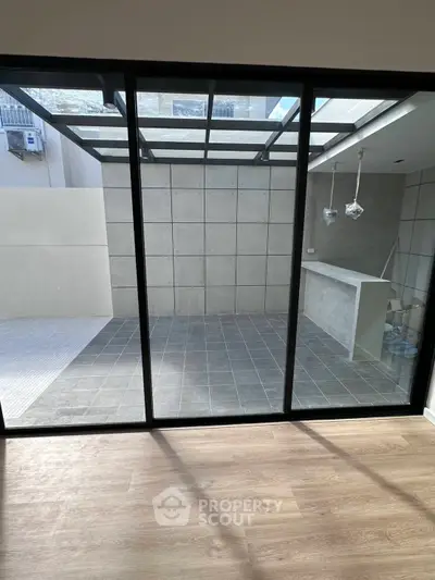 Modern patio with glass doors and sleek tile flooring, perfect for outdoor entertaining.