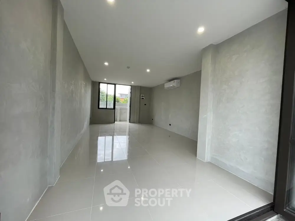 Spacious modern living room with sleek tile flooring and large windows for natural light.