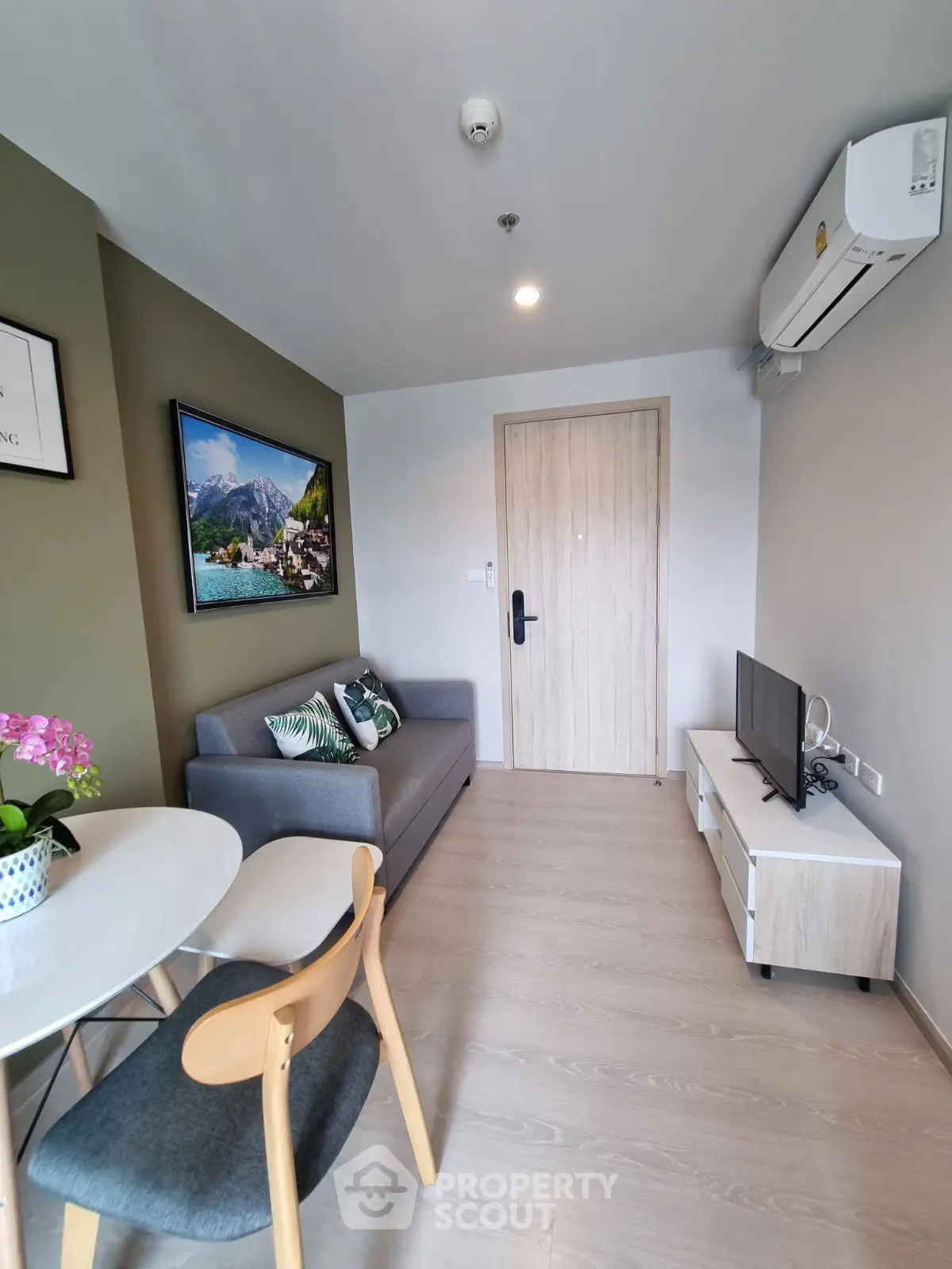 Modern living room with stylish decor, air conditioning, and cozy seating in a compact apartment.