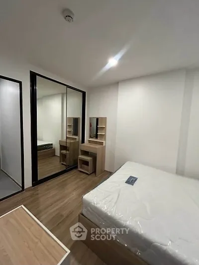 Modern bedroom with mirrored wardrobe and wooden furniture in a cozy apartment.