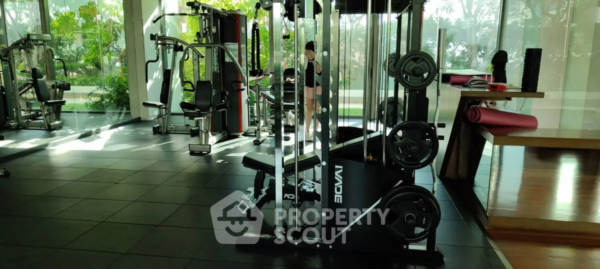 Modern gym with state-of-the-art equipment and lush garden views, perfect for fitness enthusiasts.
