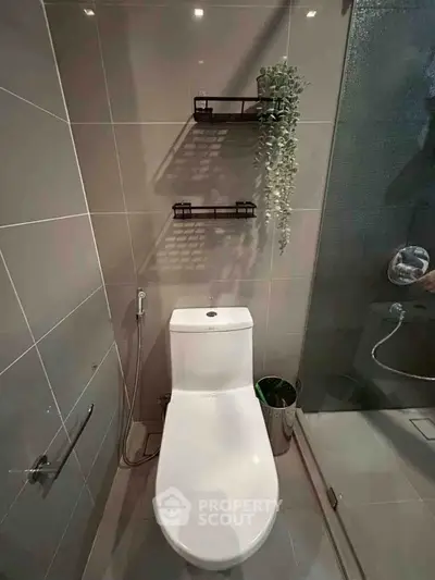 Modern bathroom with sleek design, featuring a toilet, shower, and stylish wall shelves.
