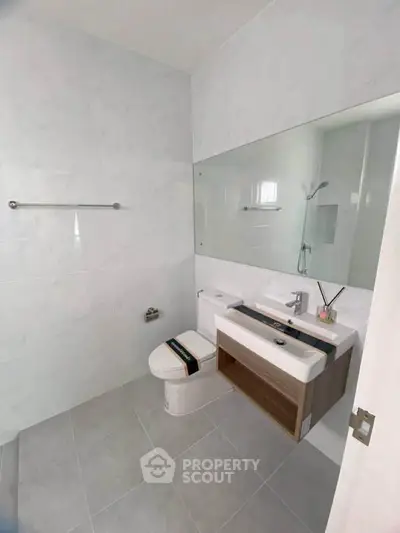 Modern bathroom with sleek fixtures and large mirror in a contemporary home.