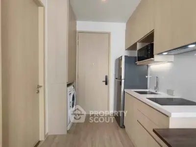 Modern kitchen with sleek appliances and wood cabinetry in a compact layout.