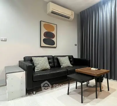 Modern living room with black leather sofa, stylish artwork, and air conditioning unit.