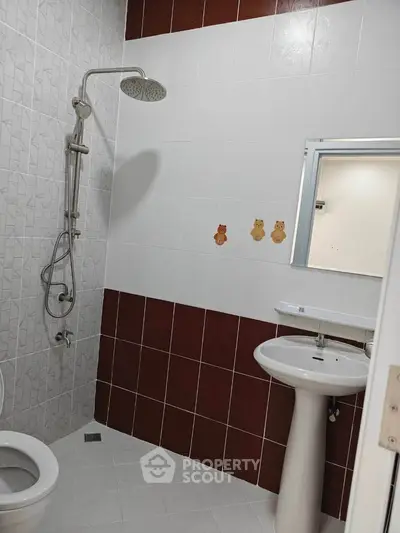 Modern bathroom with shower and pedestal sink, featuring playful wall decals.
