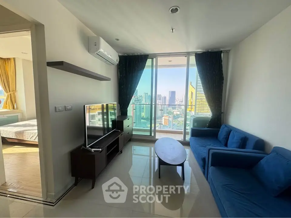 Modern living room with city view, blue sofa, and large TV, perfect for urban living.