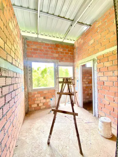 Bright unfinished room with exposed brick walls and large windows, showcasing potential for customization.
