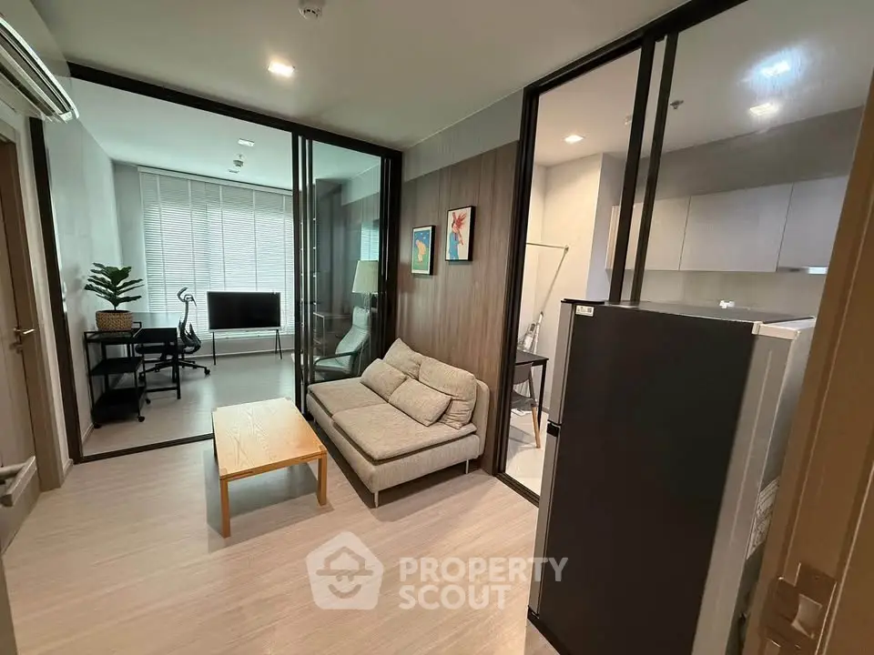Modern living room with glass partitions, cozy sofa, and sleek kitchen area in a stylish apartment.