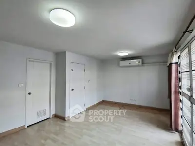 Spacious empty room with wooden flooring and air conditioning