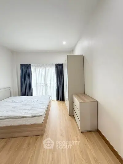 Spacious minimalist bedroom with wooden flooring and natural light