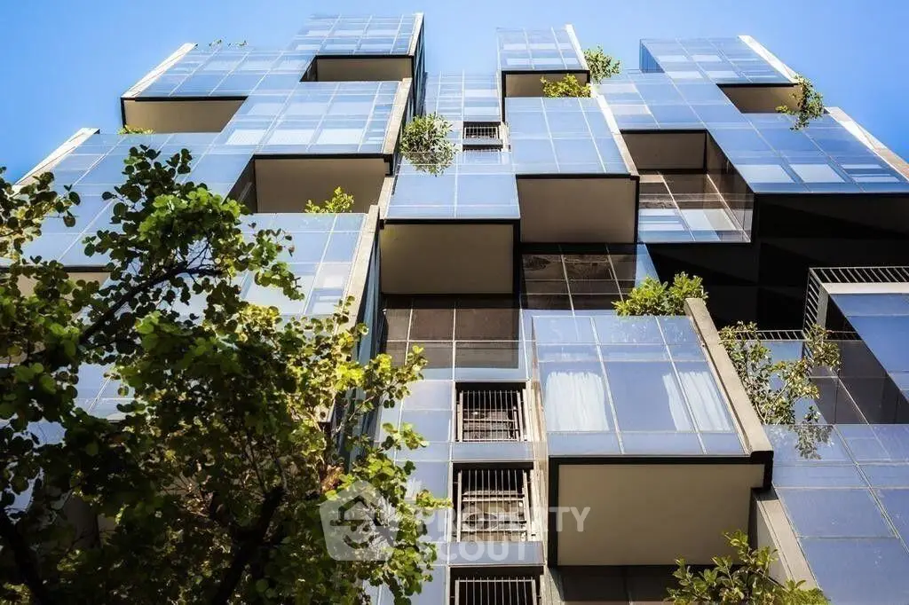Modern architectural building with glass facade and greenery, showcasing contemporary urban living.