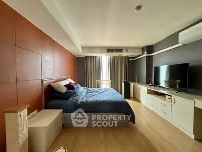 Spacious bedroom with modern decor and large TV, perfect for relaxation.