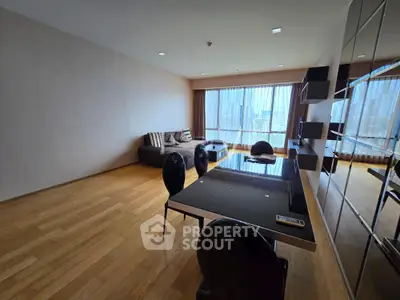 Spacious modern living room with hardwood floors and large windows offering city views.