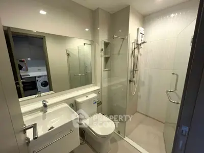 Modern bathroom with glass shower and sleek fixtures in contemporary apartment.