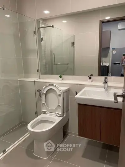 Modern bathroom with glass shower and sleek fixtures in contemporary apartment.