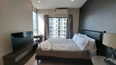 Modern bedroom with large window and city view, featuring a sleek TV and cozy bedding.