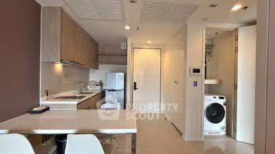 Modern kitchen with sleek appliances and compact laundry area in stylish apartment.