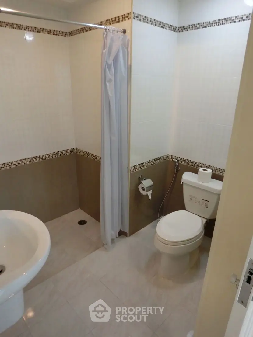 Modern bathroom with shower curtain and tiled walls in a real estate property.
