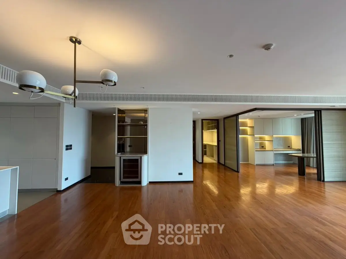 Spacious modern living room with wooden flooring and elegant lighting in a luxury apartment.