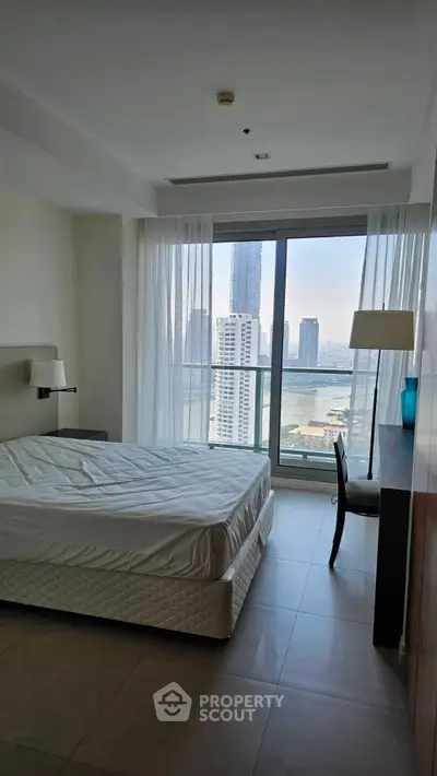 Spacious bedroom with stunning city view and modern furnishings in high-rise apartment.