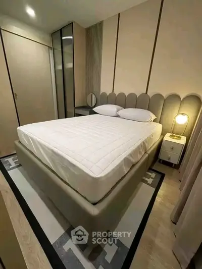 Modern bedroom with stylish bed and ambient lighting in a cozy apartment.