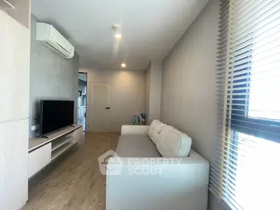 Modern living room with sleek design, featuring a comfortable sofa, flat-screen TV, and air conditioning.