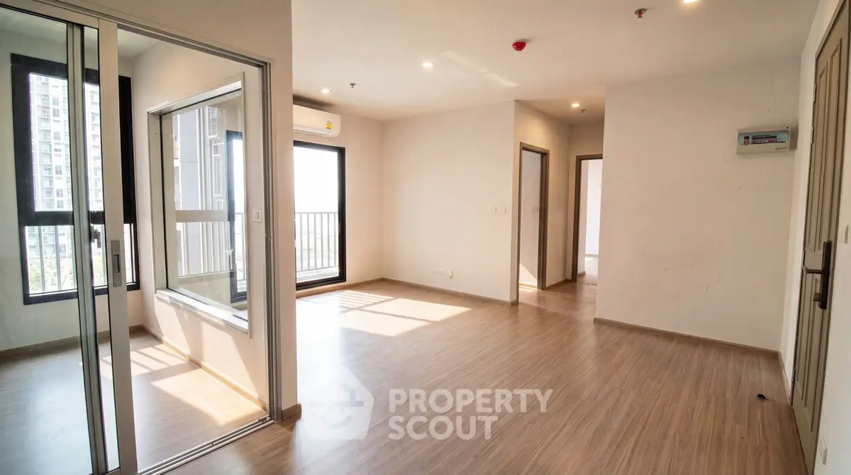 Spacious modern apartment with wooden flooring and large windows offering ample natural light.