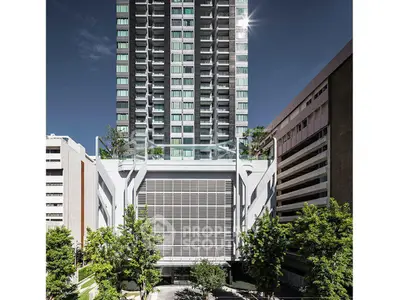 Modern high-rise building with sleek design and lush greenery in urban setting.