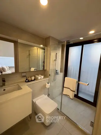 Modern bathroom with glass shower and sleek fixtures in contemporary home.