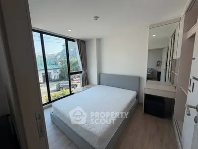 Modern bedroom with large window and stylish furniture in a bright apartment.
