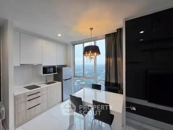 Modern kitchen with dining area and city view, featuring sleek cabinetry and elegant lighting.