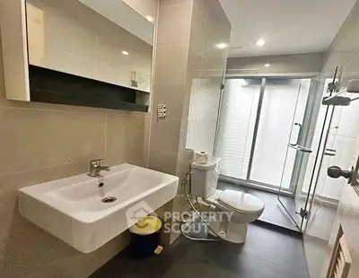 Modern bathroom with sleek fixtures and glass shower enclosure in a contemporary apartment.