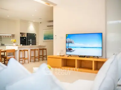 Luxurious open-plan living room with modern kitchen and large TV, perfect for entertaining.