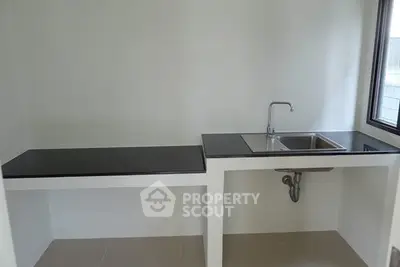 Minimalist kitchen with sleek black countertops and stainless steel sink