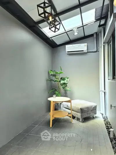 Modern enclosed balcony with natural light, featuring a cozy seating area and stylish decor.