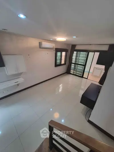 Spacious modern living room with sleek tile flooring and large windows for natural light.