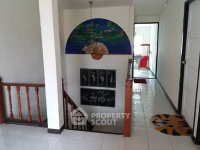 Charming interior hallway with artistic decor and wooden railing, leading to a bright room.