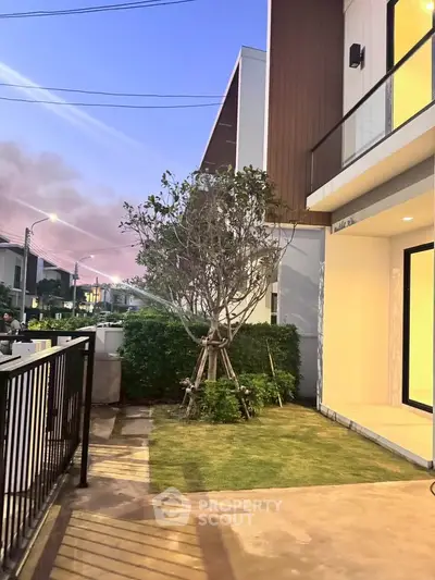 Modern townhouse exterior with landscaped garden and evening sky view.