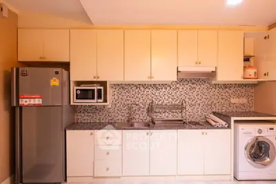 Modern kitchen with sleek appliances and mosaic backsplash in a cozy apartment.