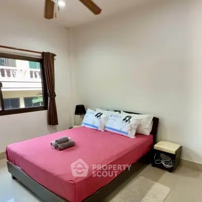 Cozy bedroom with pink bedding and natural light, ideal for relaxation and comfort.