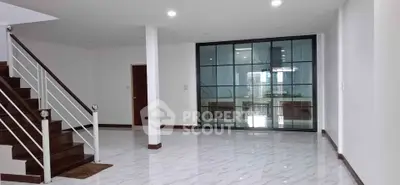 Spacious modern interior with elegant staircase and glass partition, perfect for stylish living.