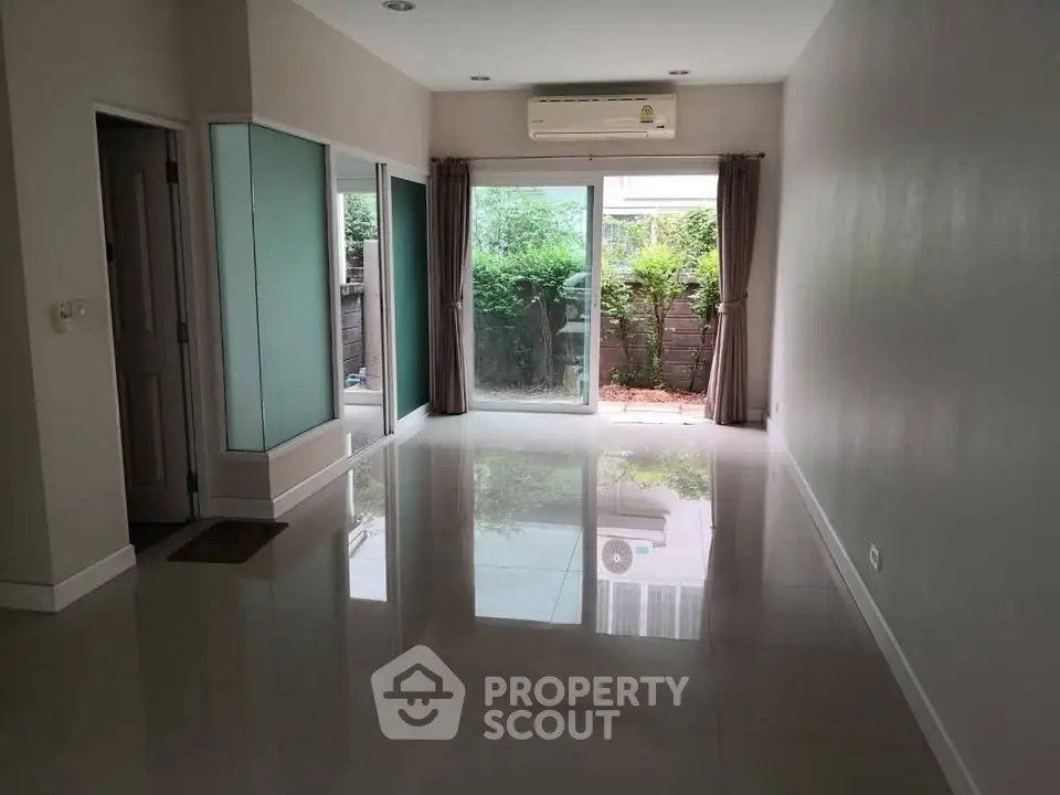 Spacious living room with large windows and garden view, perfect for natural light lovers.
